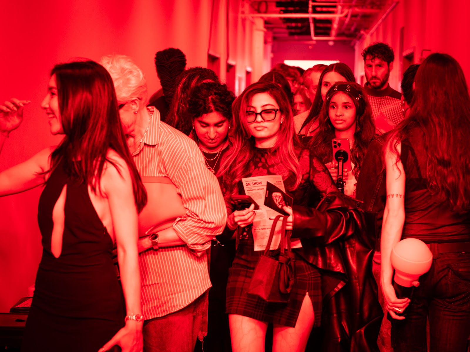 Le public dans le corridor éclairé en rouge à ON SHOW — Semaine de la mode de Montréal, photographié par Sergio Vega Perry.