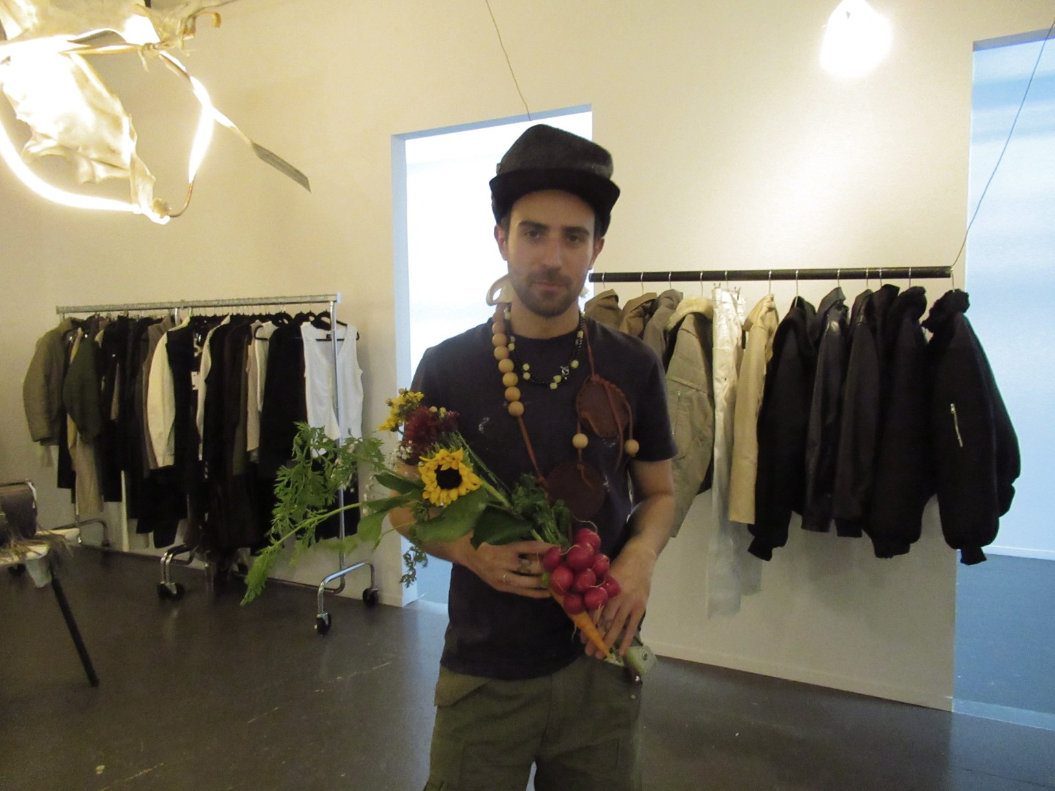 Une personne tenant des fleurs dans le showroom, près des portants et de l’éclairage sculptural.
