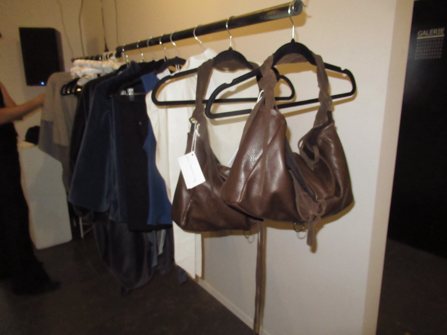 Sacs bruns, crème, bleus et noirs suspendus au showroom LDF.