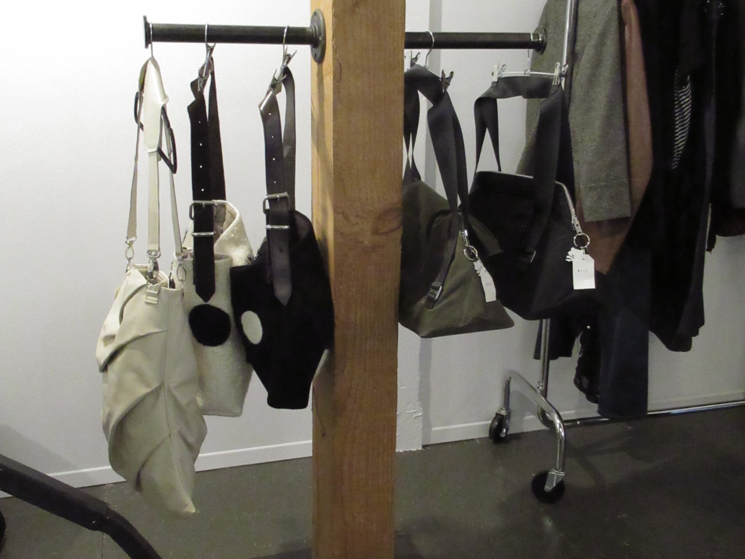 Sacs noirs et crème disposés sur un portant au showroom LDF.