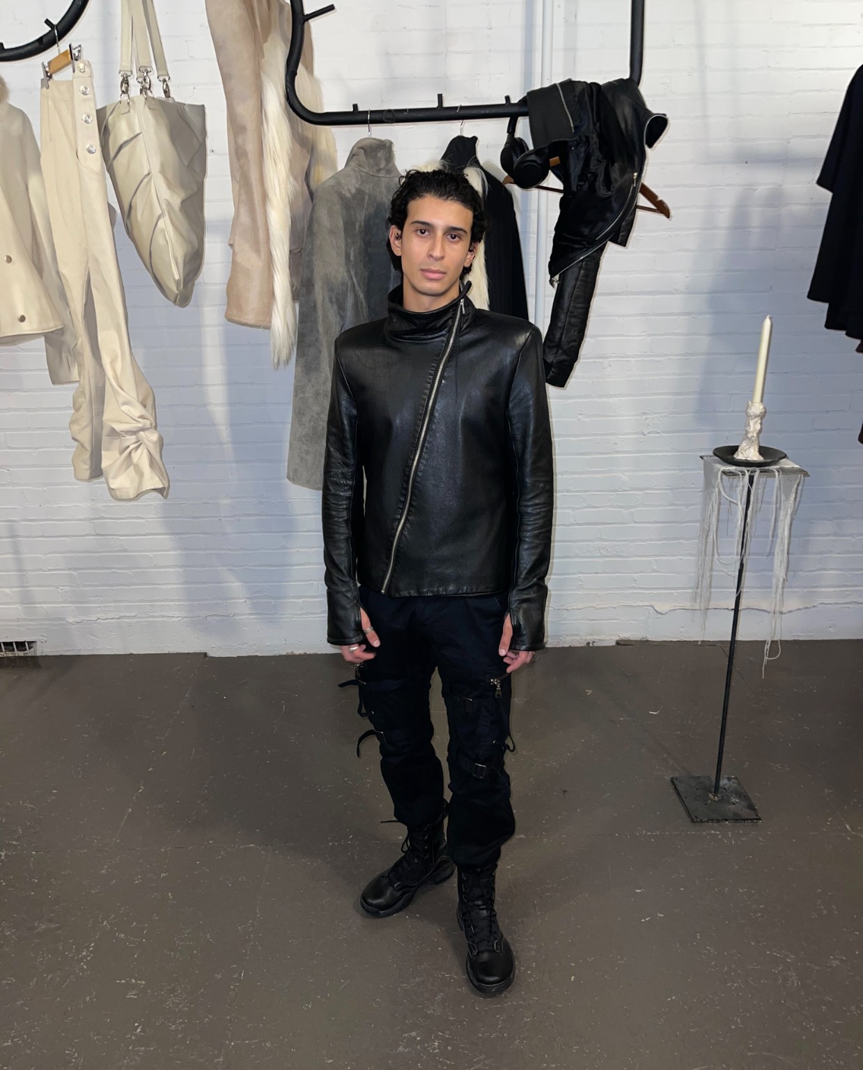 Une personne en veste de cuir noire devant les vêtements de créateurs au showroom LDF, Semaine de la mode de Montréal 2026.