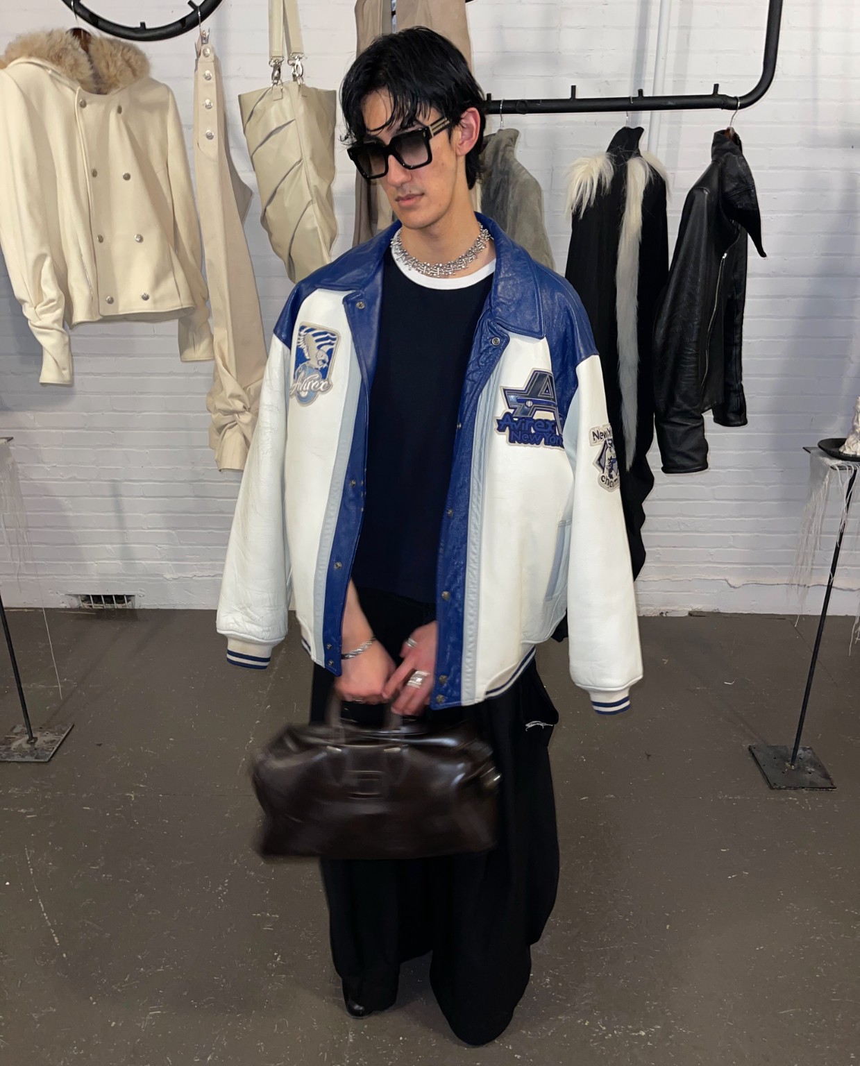 Une personne en veste universitaire bleue et blanche au showroom LDF, Semaine de la mode de Montréal 2026.